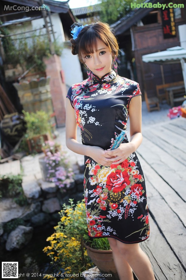 A woman in a black dress standing on a wooden deck.