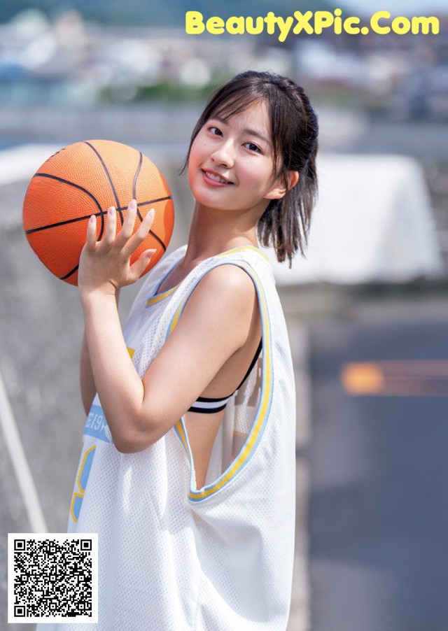 A young woman holding a basketball in her hand.